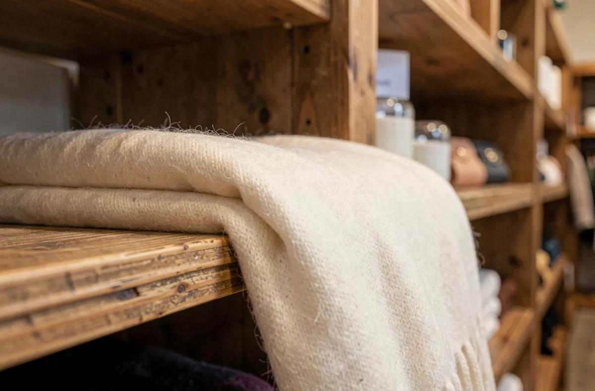 Écharpe en cachemire ivoire soigneusement pliée sur une étagère en bois dans une boutique de luxe